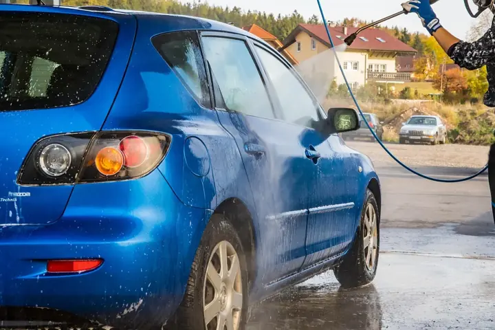 A car being cleaned with a high-pressure washer wand